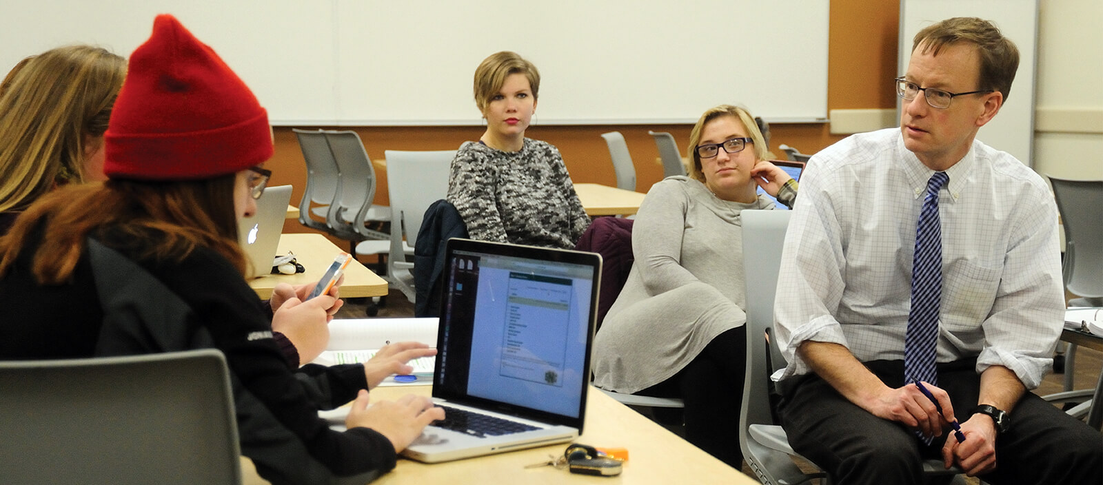 A professor speaks to a group of students in a classroom.