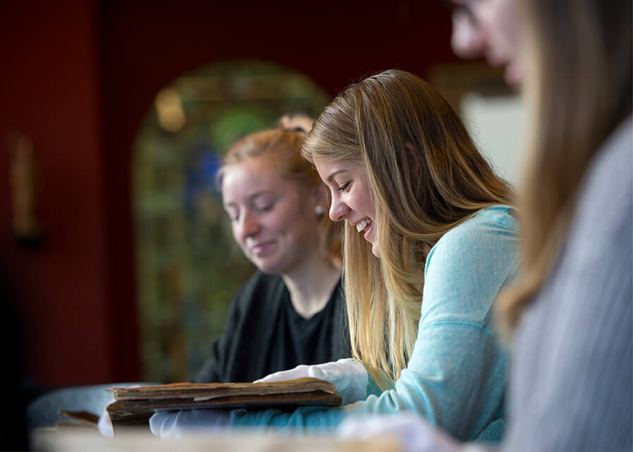 Students reading a book and smiling