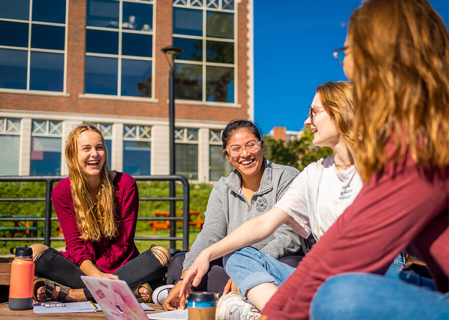 Students sitting on the deck talking and smiling