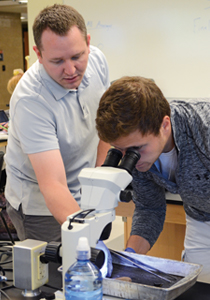 Ryan King helps student with microscope